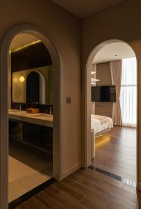 a bedroom with a bed and a bathroom with a mirror at AMANA Hotel Phan Thiet in Ấp Bình Hưng