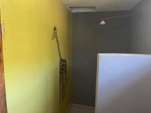 a giraffe stencil on a wall in a room at Lake Natron Maasai Guesthouse in Mtowabaga
