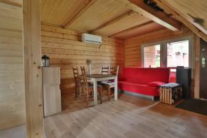 a living room with a red couch and a table at Całoroczny, drewniany domek przy lesie in Prażmów
