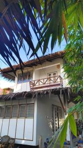 a white house with a balcony and some trees at Casa del mar house in Paje