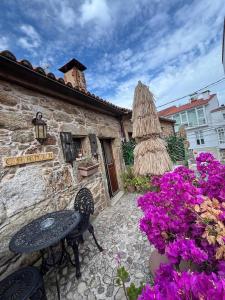 a stone building with a table and purple flowers at Casa de Carmen in Corcubión