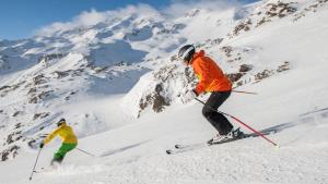 duas pessoas a esquiar numa montanha coberta de neve em Evenia Monte Alba em Cerler