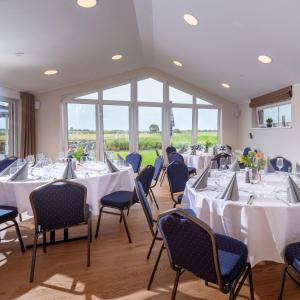 胡苏姆Nordsee-Hotel Arlau-Schleuse的一间有白色桌椅和窗户的房间