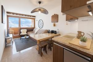 eine Küche und ein Wohnzimmer mit einem Tisch und einer Couch in der Unterkunft Smartstay Caron - Val Thorens in Val Thorens