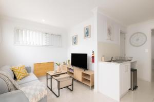 a white living room with a couch and a tv at Smart Suites Self Check-in Apartments - S Freney in Brisbane