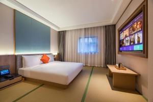 a hotel room with a bed and a flat screen tv at Manxin Hotel Beijing Lama Temple in Beijing