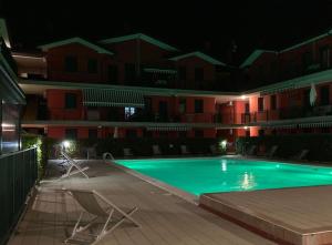 an empty swimming pool at night with two lawn chairs at Green oasis close to the center in Rosolina Mare
