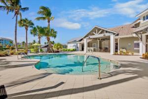 a swimming pool in front of a house with palm trees at One Happy Condo in Bradenton