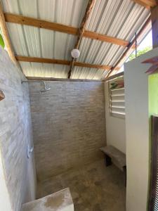 a bathroom with a shower with a brick wall at Caribbean House in Sarteneja