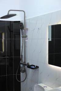 a shower in a bathroom with black and white tiles at McMillan Hotel in Entebbe