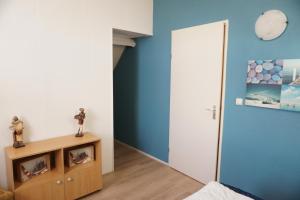a bedroom with a blue wall and a wooden cabinet at Kustverhuur , Park Scheldeveste, Zwin 143 in Breskens +15 photos