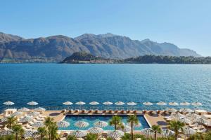 a view of a pool with umbrellas and the ocean at The Lake Como EDITION in Griante Cadenabbia