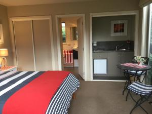 a bedroom with a bed and a table and a kitchen at hawea river retreat in Albert Town