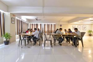 a group of people sitting at tables in a restaurant at Via Apollo - Nr Odhav Ring Road in Naroda