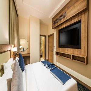 a hotel room with a large bed with a flat screen tv at Sunday Luxury Central formerly Anan hotel in Riyadh