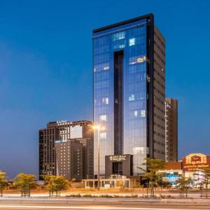 a tall glass building in a city at night at Sunday Luxury Central formerly Anan hotel in Riyadh