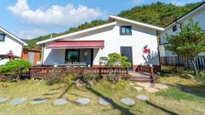 a white house with a porch with a deck at Gyeongju Hiltopia Kids Pool Villa in Gyeongju