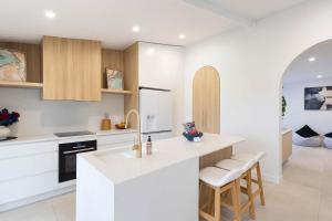 een witte keuken met een aanrecht en krukken bij Perfection in Pallarenda With Pool & Studio Apt in Pallarenda