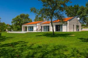 ein Haus mit einem orangefarbenen Dach auf einem grünen Hof in der Unterkunft Villa Vista Verde in Majkusi