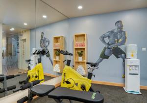a gym with exercise bikes and a mural of a man at Bloom Hotel - Whitefield in Bangalore