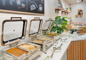 a buffet line with trays of food on a counter at Bloom Hotel - Whitefield in Bangalore +21 photos
