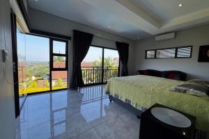 a bedroom with a bed and a balcony with large windows at The Coastal Charm Villa in Ballito +33 photos