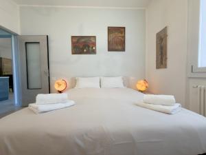 a large white bed in a white room with two lamps at Quiet Home in Val Brona in Valbrona
