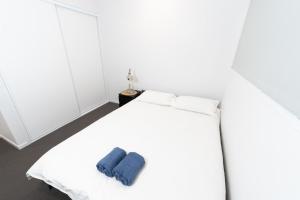 una camera da letto con un letto bianco e un asciugamano blu di Modern Park Ridge Haven – Perfect for Families! a Marsden