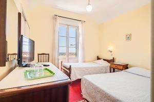 a hotel room with two beds and a television at Mirasol Guesthouse in Funchal