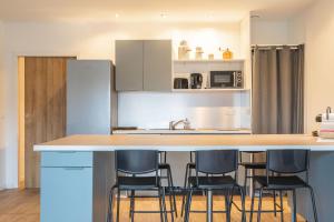 een keuken met een aanrecht met vier barkrukken bij L'instant fleuri in Saint-Hippolyte