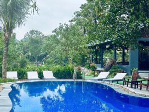 een zwembad met witte stoelen en een tafel bij Hidden Rock Tam Coc in Vũ Lâm