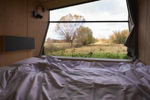 una cama en una habitación con una ventana grande en Sleep Space 2 - Green&Tiny Spot Osterwieck Birkenmühle, en Osterwieck