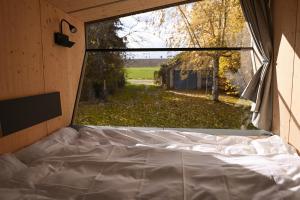 una cama en una habitación con una ventana grande en Sleep Space 1 - Green&Tiny Spot Osterwieck Birkenmühle, en Osterwieck