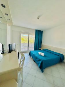 a bedroom with a blue bed and a desk and a television at Hotel Miralonga in La Maddalena +13 photos