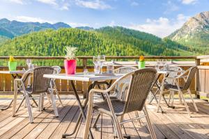 une table et des chaises sur une terrasse avec des montagnes en arrière-plan dans l'établissement Anova Hotel & Spa, à Montgenèvre