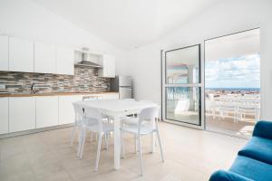 een keuken en eetkamer met een witte tafel en stoelen bij Girasole in La Caletta +15 foto's