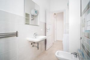 een witte badkamer met een wastafel en een spiegel bij Girasole in La Caletta