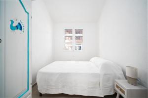 een witte slaapkamer met een bed en een raam bij Girasole in La Caletta