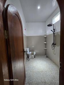 a bathroom with a toilet and a wooden door at Pinggan Chill Out Kintamani in Gretek