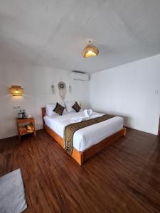a bedroom with a large bed and a wooden floor at SEAVIEW Bungalow & Resto in Sekotong