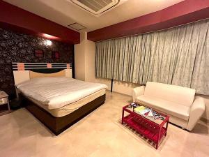 a bedroom with a bed and a couch and a chair at ホテルクレアトゥール安城 in Wada