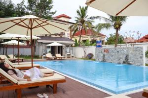a woman laying on lounge chairs next to a swimming pool at Dara Express Inn by Angkor Green Gardens in Phumĭ Thnál
