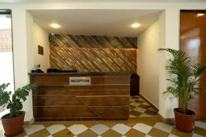 a reception desk in a lobby with two plants at Kesar Villa By DSR Group in Bedla