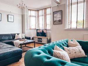 a living room with a blue couch and a tv at Ty-Fry House, by Solace Stays in Cardiff