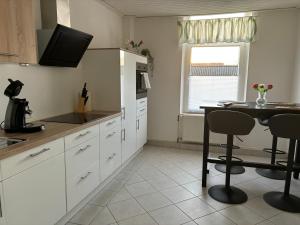 une cuisine avec des armoires blanches et une table avec des chaises dans l'établissement Landblick, à Ovelgönne