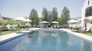 ステレンボッシュにあるWinelands Golf Lodges 15の建物の隣にスイミングプール(椅子、パラソル付)