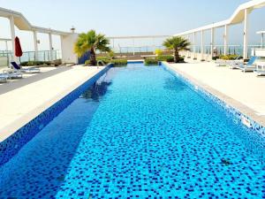 a swimming pool with blue water in a building at Modern studio with Beach and Pool in Al Marjan Island in Ras al Khaimah