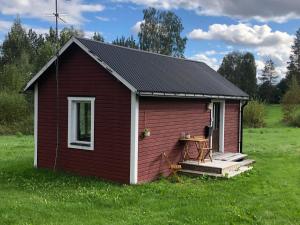 ein kleiner roter Schuppen mit einem Tisch auf einem Feld in der Unterkunft Ölrun Stuga in Hammarstrand