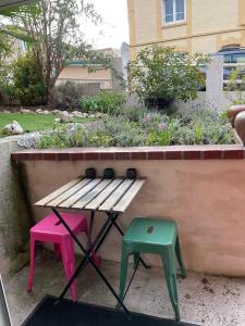 a wooden bench and two stools in a garden at La Maison Rouge in Trouville-sur-Mer