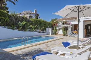 una piscina con sillas blancas y sombrilla en Casa del Limonero, en El Tosalet